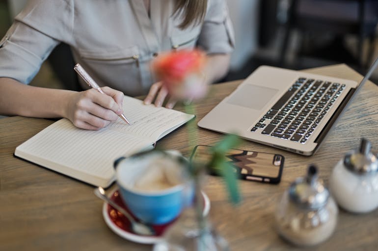 a woman writing down goals before mastering content audits